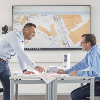 Zwei Citycom Mitarbeiter, die über Pläne gebeugt sind und diese besprechen