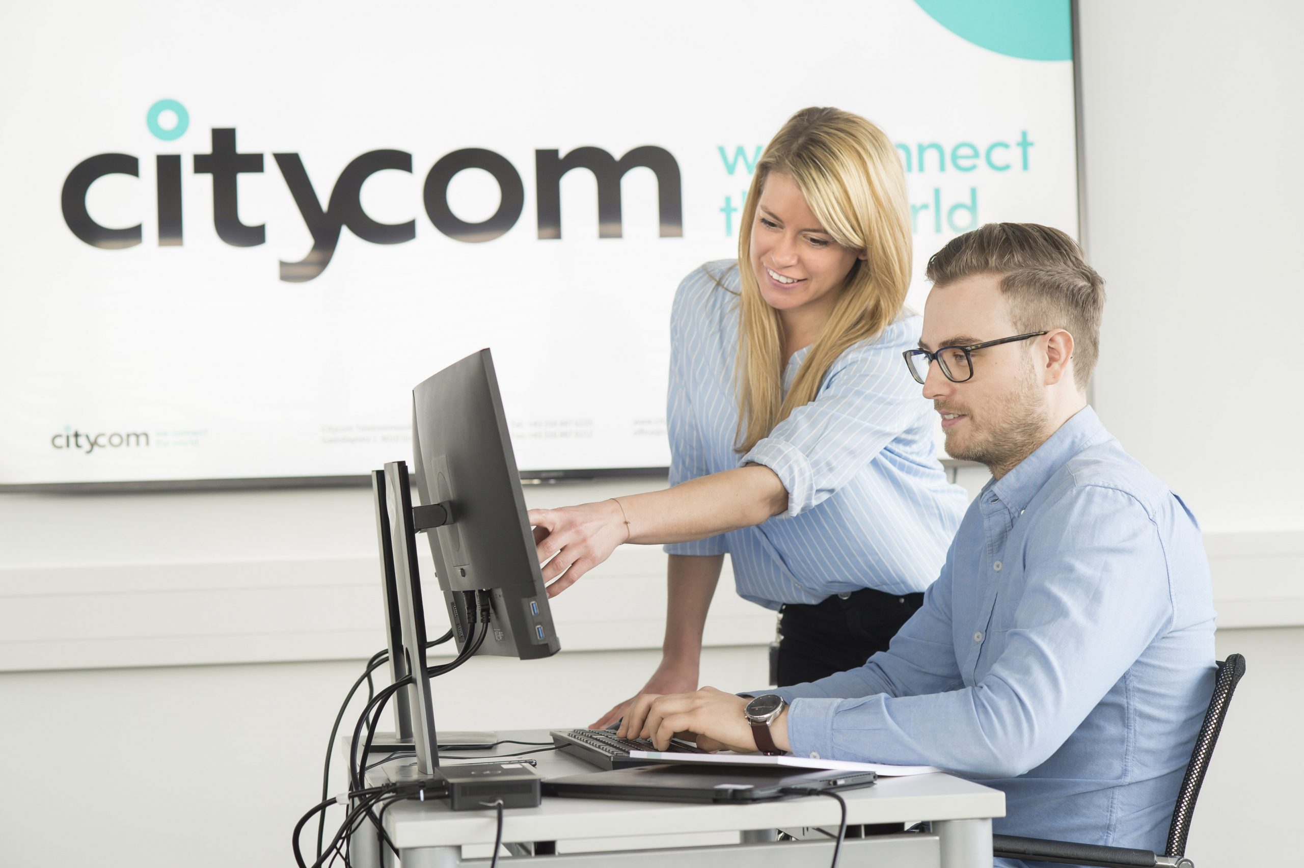 Citycom Mitarbeiterin, die ihrem Kollegen etwas auf dem Bildschirm zeigt