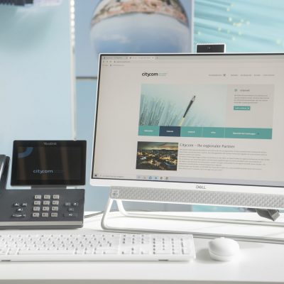 Schreibtisch mit Bildschirm auf dem die Citycom Website zu sehen ist