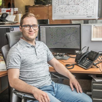 Mitarbeiter am Schreibtisch, der in die Kamera lächelt